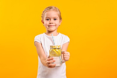 Photo of Girl with mason jar of lemonade on orange background. Refreshing drink