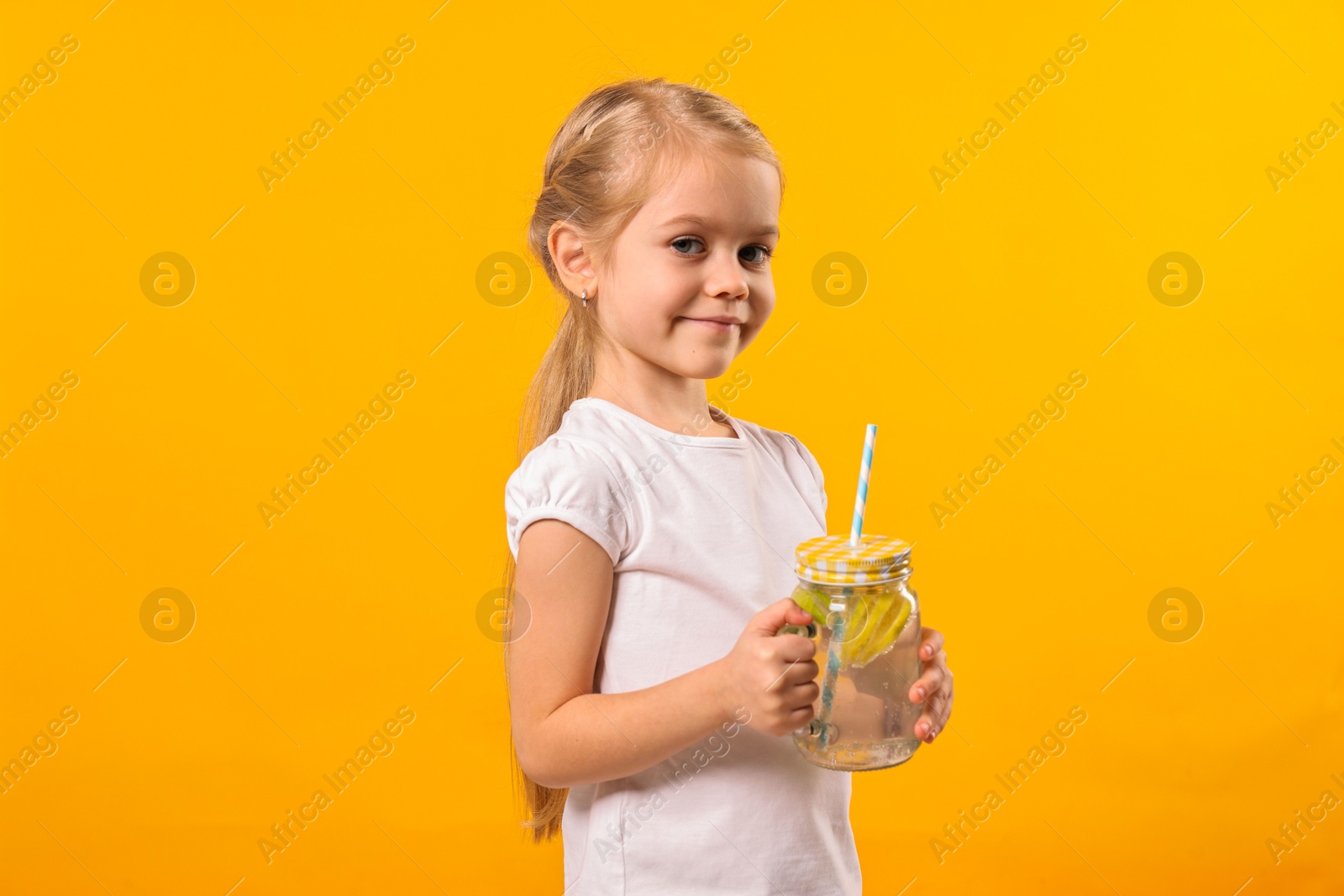 Photo of Girl with mason jar of lemonade on orange background. Refreshing drink