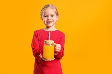 Photo of Girl with mason jar of juice on orange background, space for text. Refreshing drink