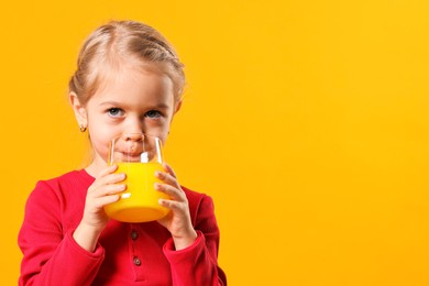 Photo of Girl drinking tasty juice on orange background, space for text. Refreshing drink