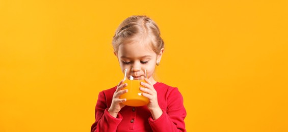 Photo of Girl drinking tasty juice on orange background. Refreshing drink