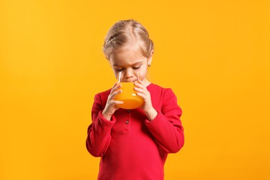 Photo of Girl drinking tasty juice on orange background. Refreshing drink