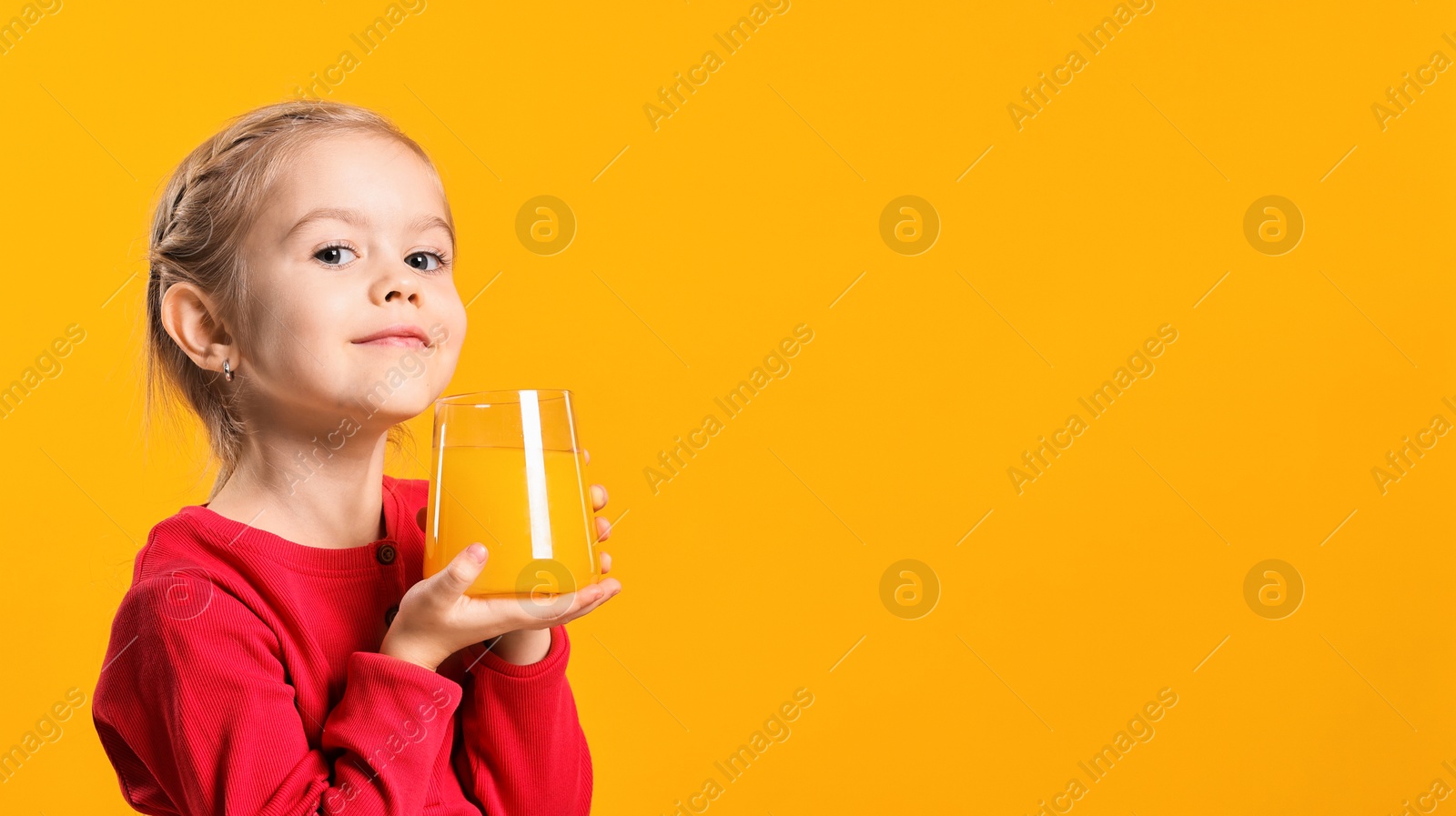 Photo of Girl with glass of juice on orange background, space for text. Refreshing drink