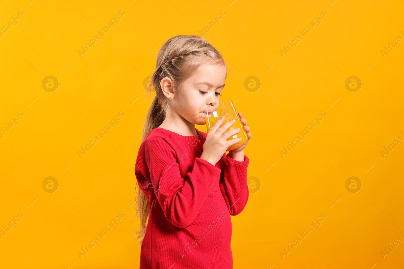 Photo of Girl drinking tasty juice on orange background. Refreshing drink