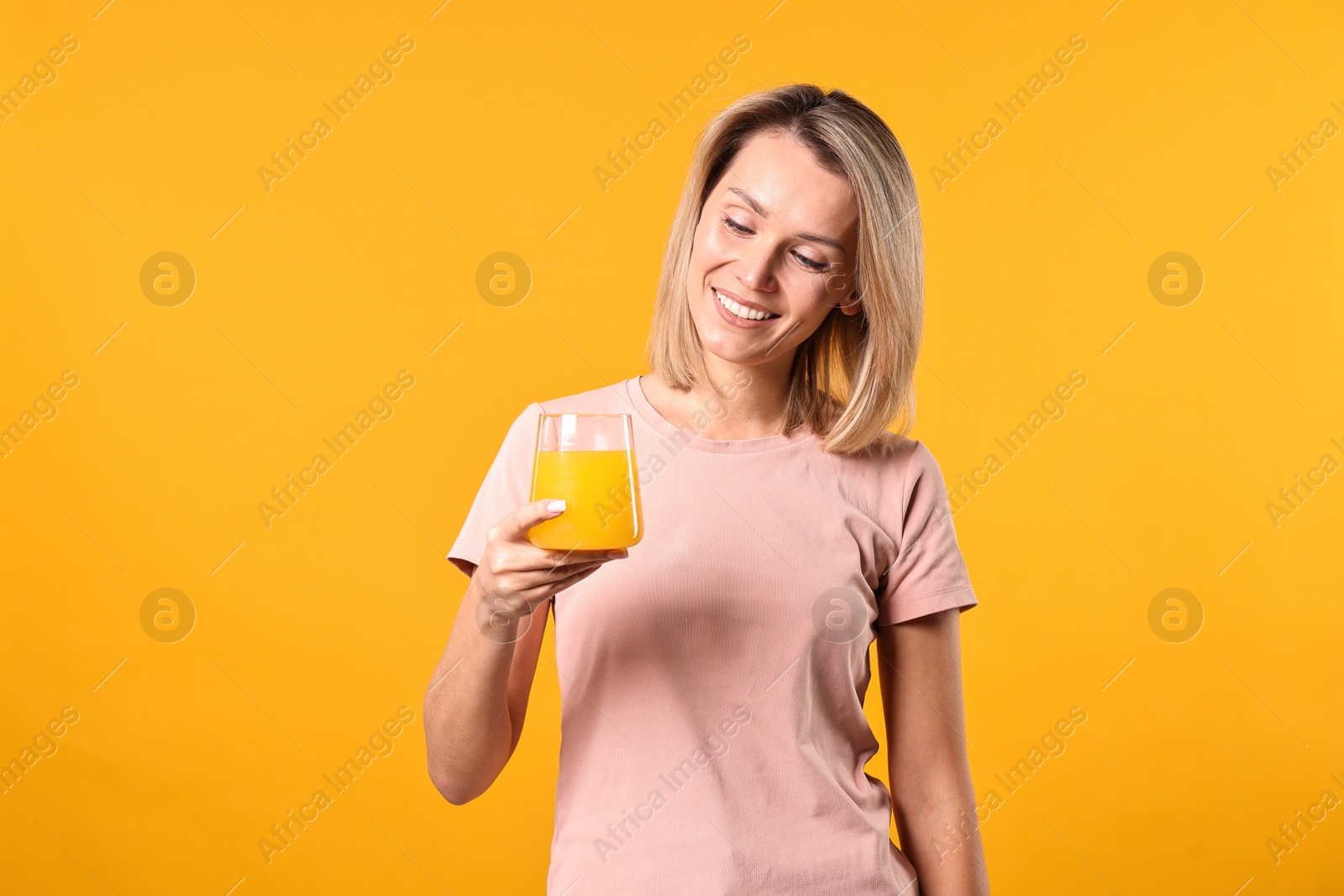 Photo of Woman with glass of juice on orange background. Refreshing drink