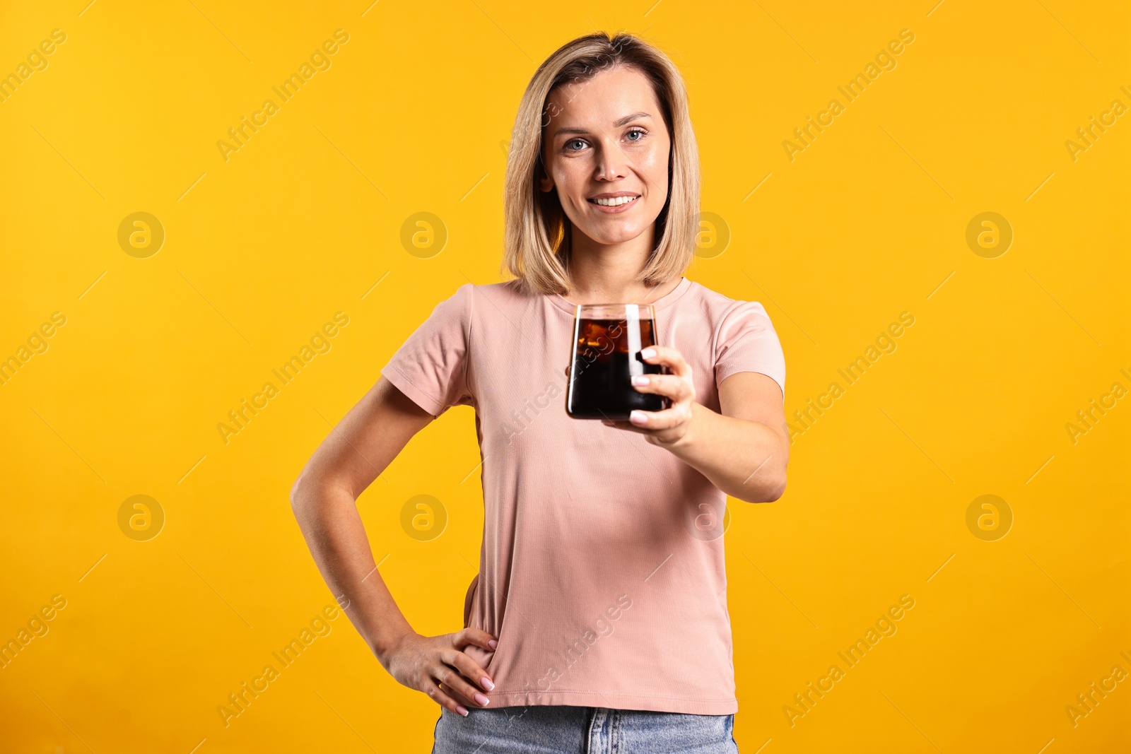 Photo of Woman with glass of refreshing soda drink on orange background.