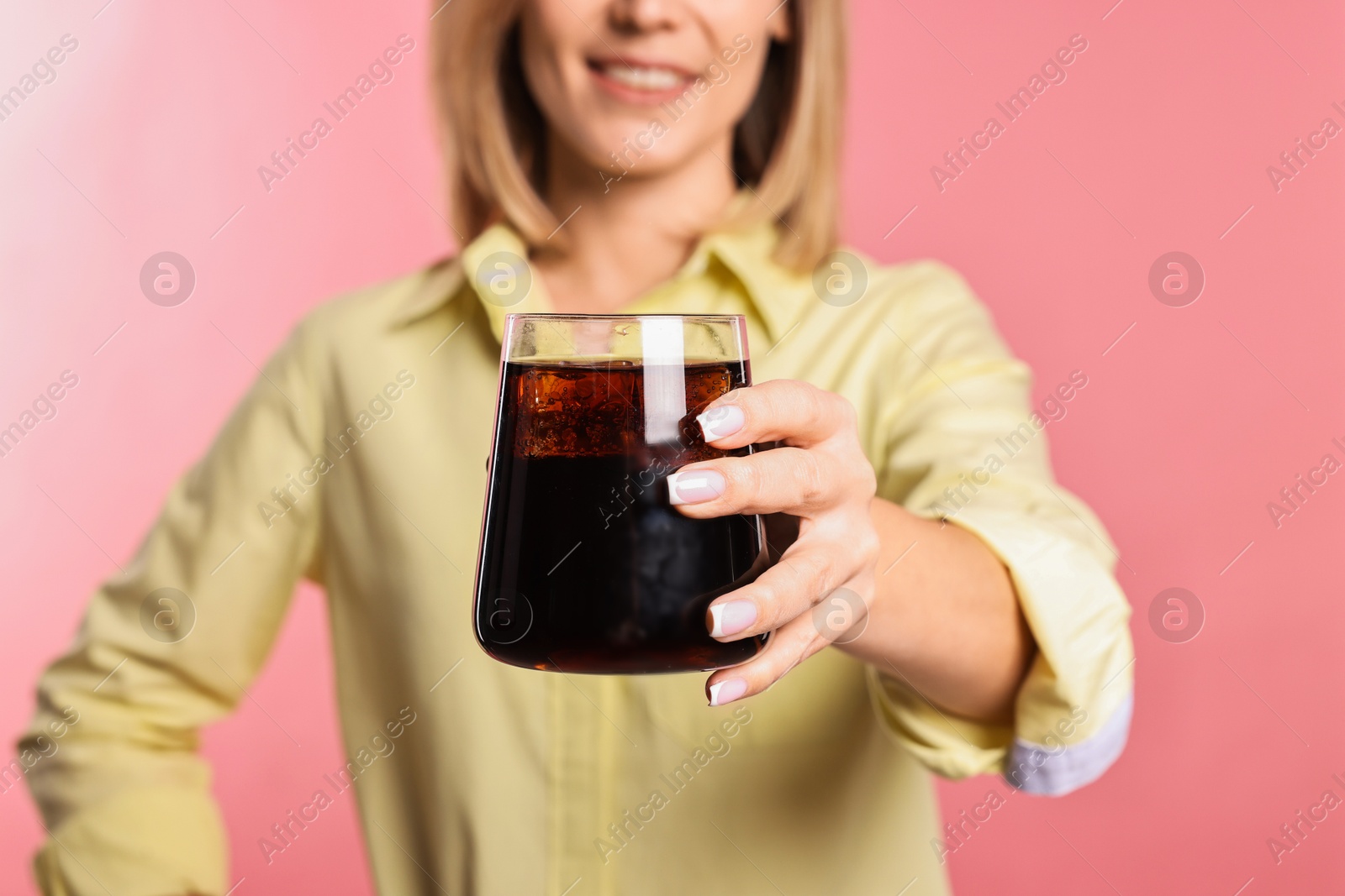 Photo of Woman with glass of refreshing soda drink on pink background, closeup