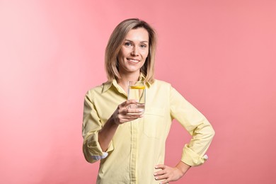 Photo of Woman with glass of lemonade on pink background. Refreshing drink