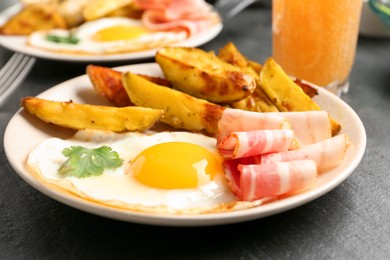 Photo of Tasty brunch. Fried egg, potato and bacon on dark textured table, closeup