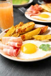 Photo of Tasty brunch. Fried egg, potato and bacon on dark textured table, closeup