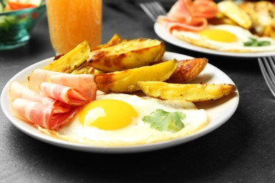 Photo of Tasty brunch. Fried egg, potato and bacon on dark textured table, closeup