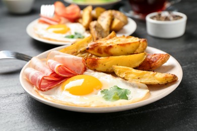 Photo of Tasty brunch. Fried egg, potato and bacon on dark textured table, closeup