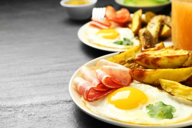 Photo of Tasty brunch. Fried egg, potato and bacon on dark textured table, closeup. Space for text