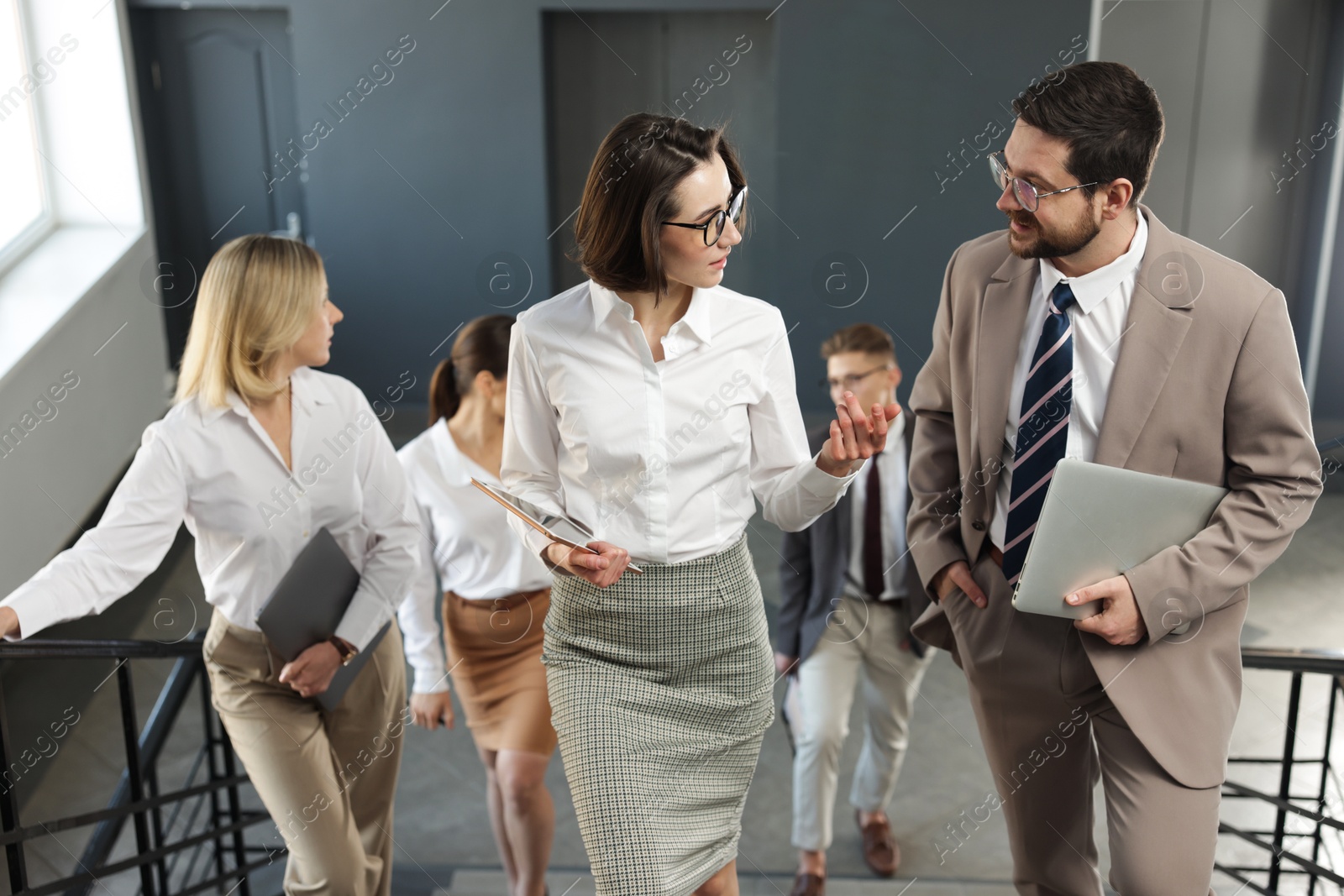 Photo of Group of coworkers walking up stairs indoors