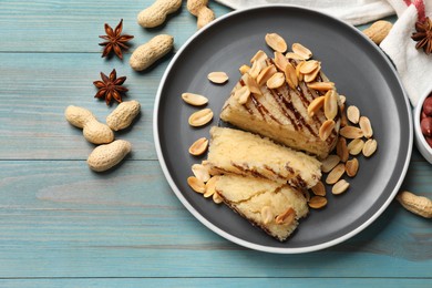 Photo of Delicious sweet semolina halva with peanuts and spices on blue wooden table, flat lay