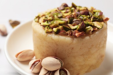 Photo of Delicious sweet semolina halva with pistachios on white table, closeup