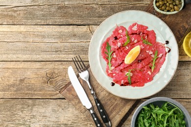 Photo of Delicious beef carpaccio served on wooden table, flat lay. Space for text