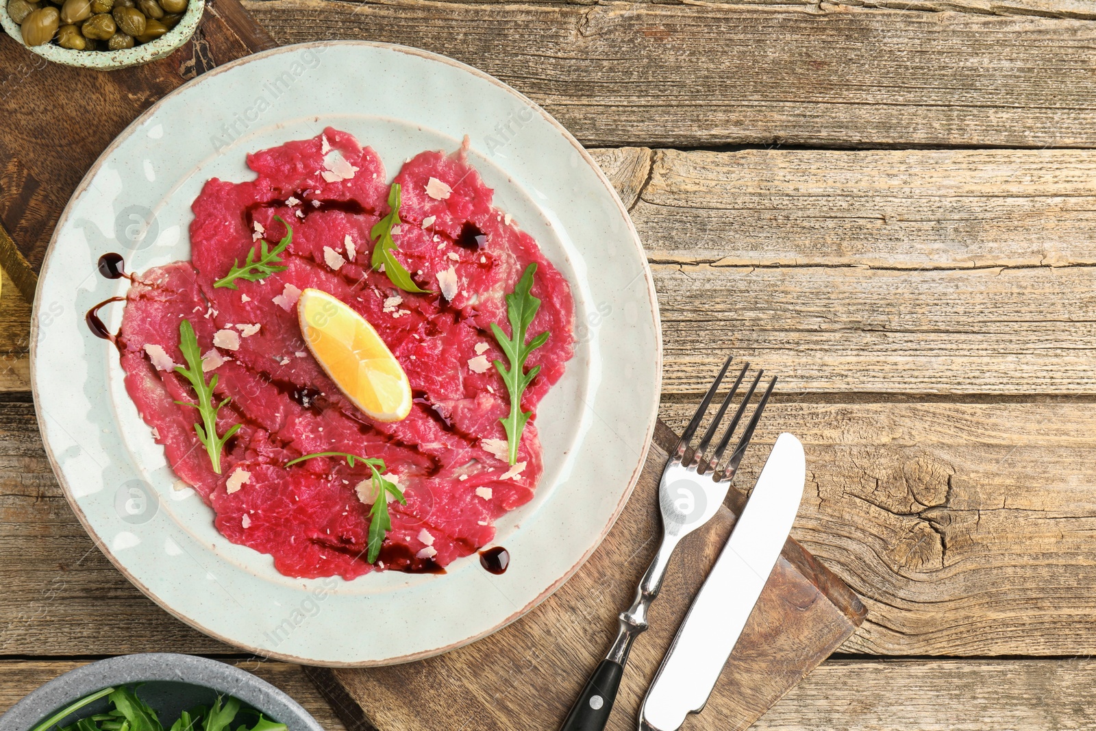 Photo of Delicious beef carpaccio served on wooden table, flat lay. Space for text