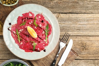 Delicious beef carpaccio served on wooden table, flat lay. Space for text