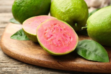 Photo of Fresh whole and cut guava fruits on wooden table, closeup