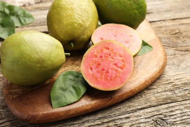 Photo of Fresh whole and cut guava fruits on wooden table, closeup