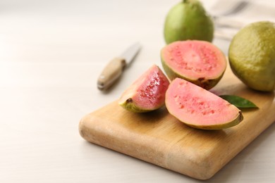 Photo of Fresh guava fruits on white wooden table, closeup. Space for text