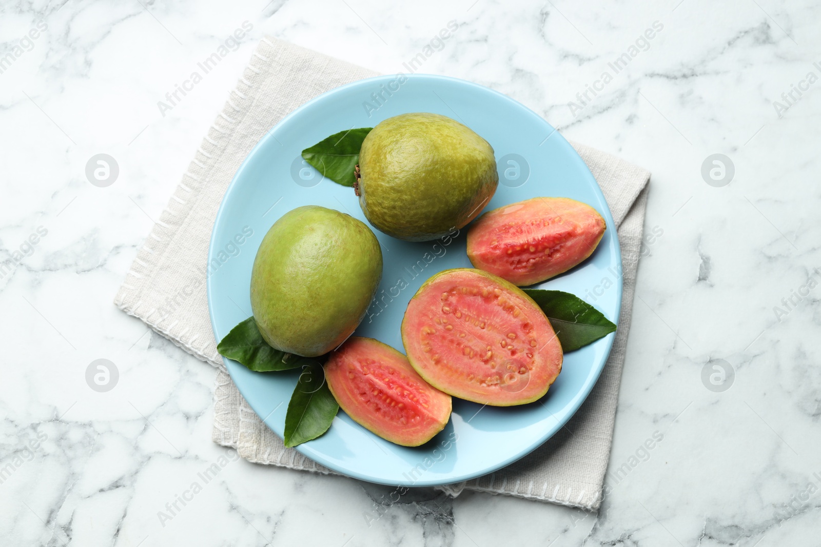 Photo of Fresh guava fruits and leaves on white marble table, top view