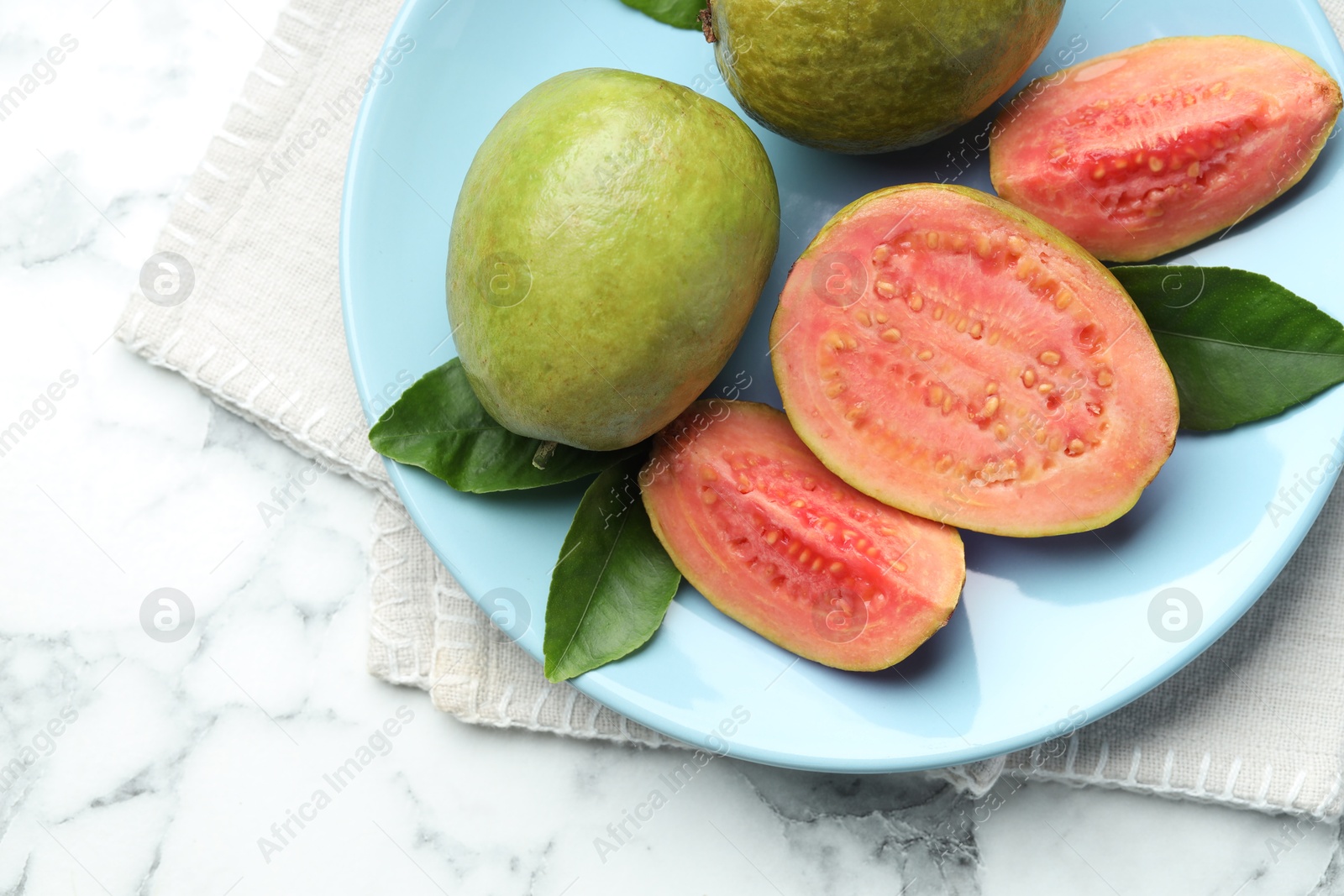 Photo of Fresh guava fruits and leaves on white marble table, top view