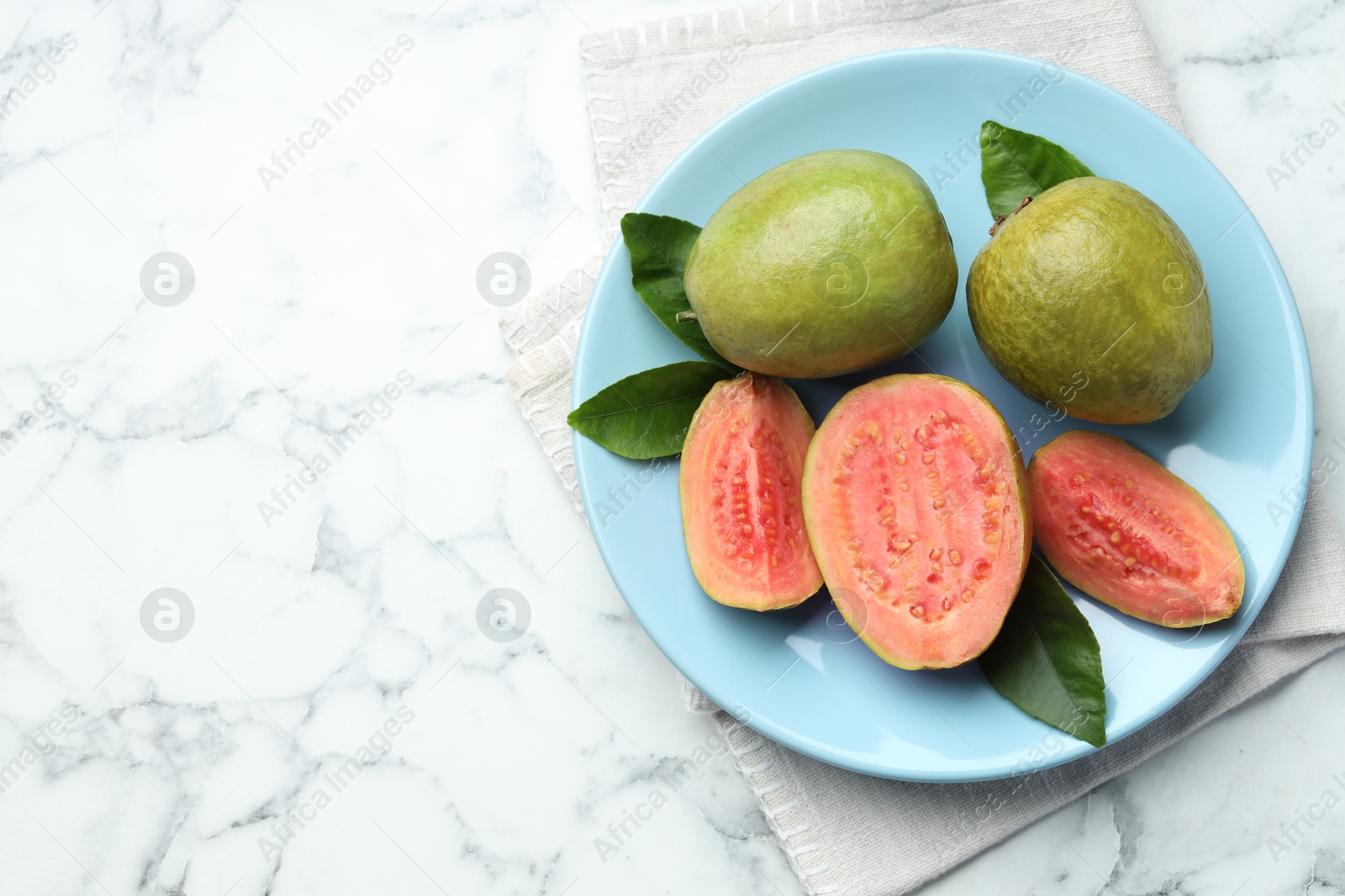 Photo of Fresh guava fruits and leaves on white marble table, top view. Space for text