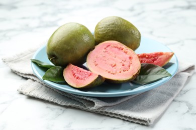 Photo of Fresh guava fruits and leaves on white marble table, closeup