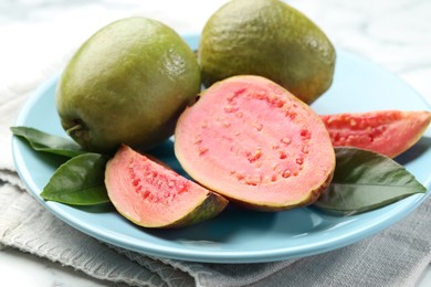 Photo of Fresh guava fruits and leaves on white table, closeup