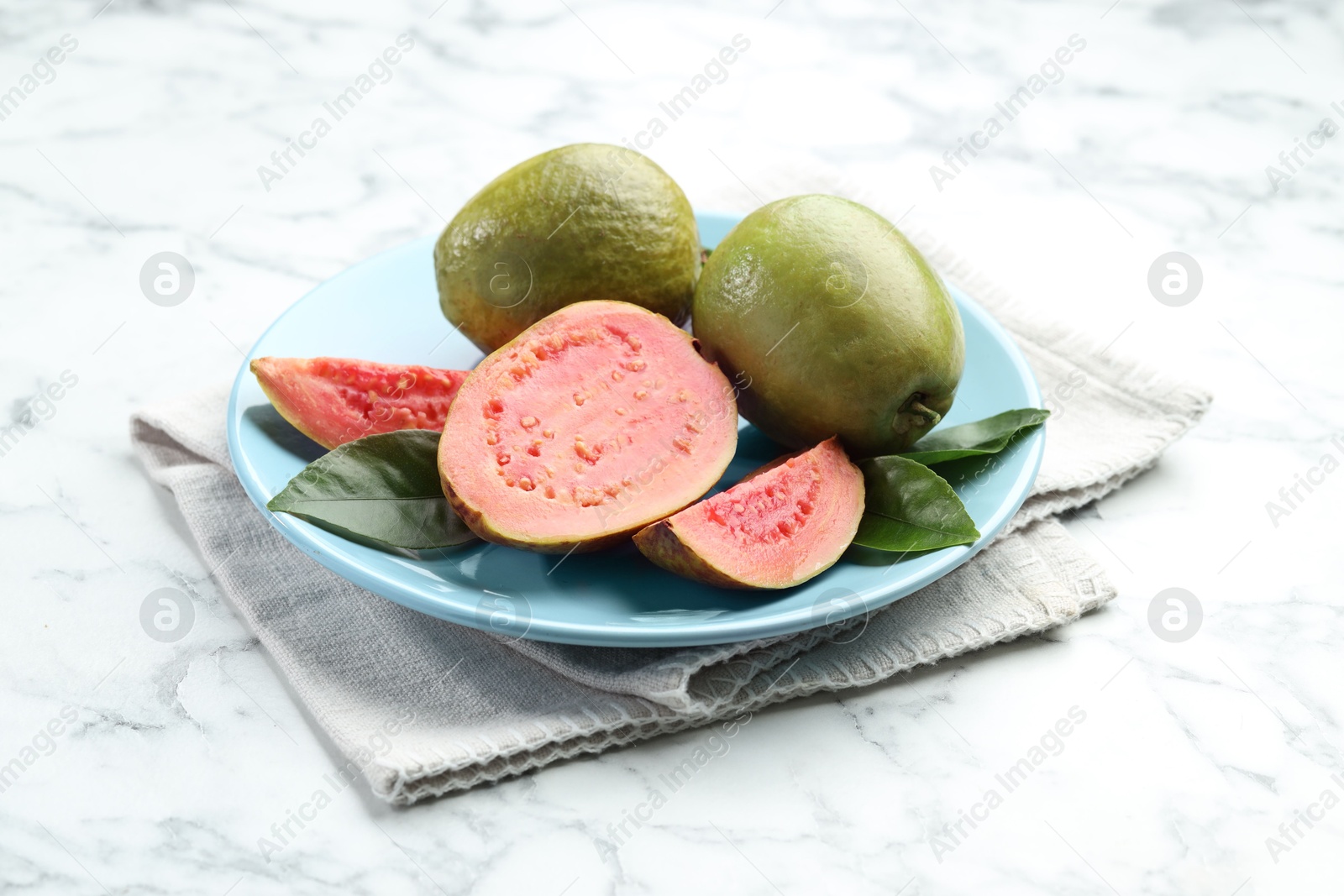 Photo of Fresh guava fruits and leaves on white marble table