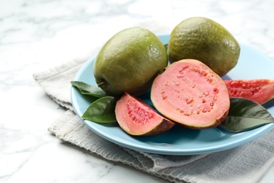 Fresh guava fruits and leaves on white marble table, closeup