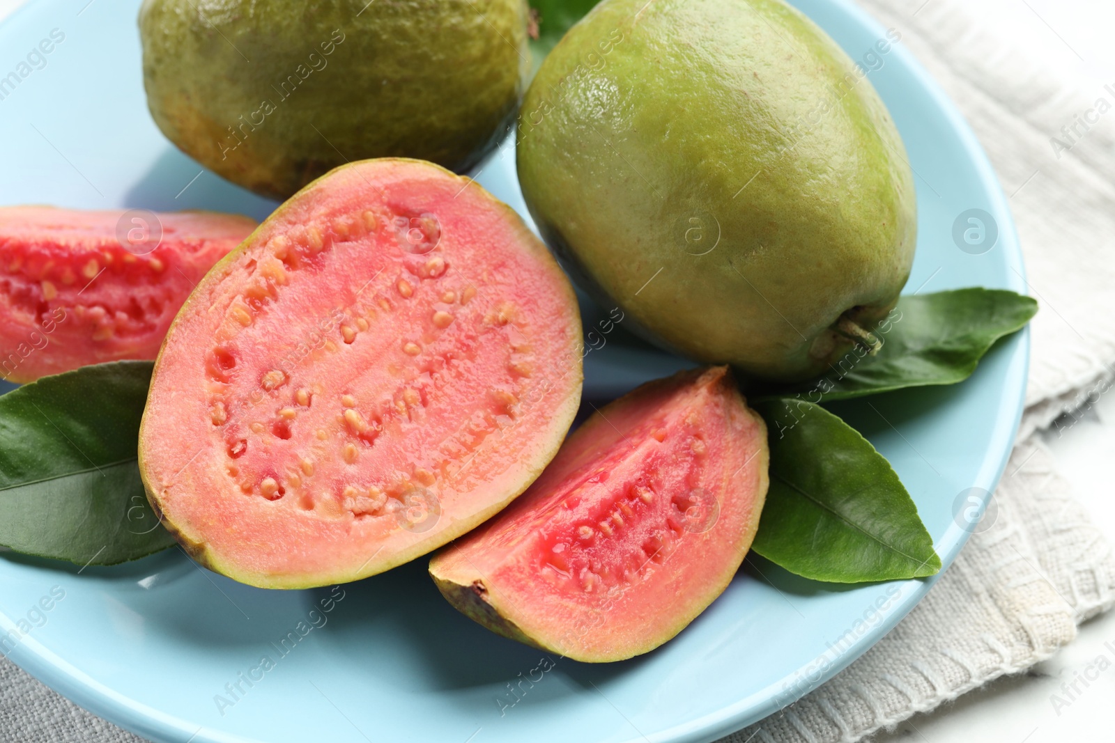 Photo of Fresh guava fruits and leaves on white table, closeup