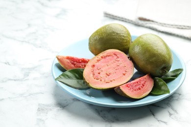 Photo of Fresh guava fruits and leaves on white marble table. Space for text