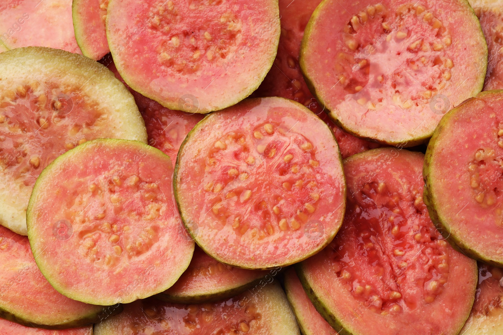 Photo of Many juicy slices of guava as background, top view