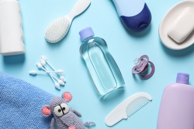 Photo of Baby oil and bath accessories on light blue background, flat lay