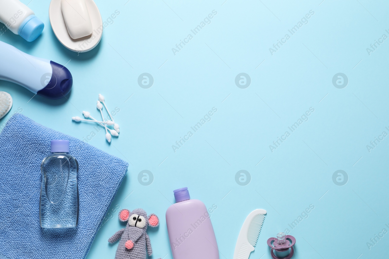 Photo of Baby oil and bath accessories on light blue background, flat lay. Space for text