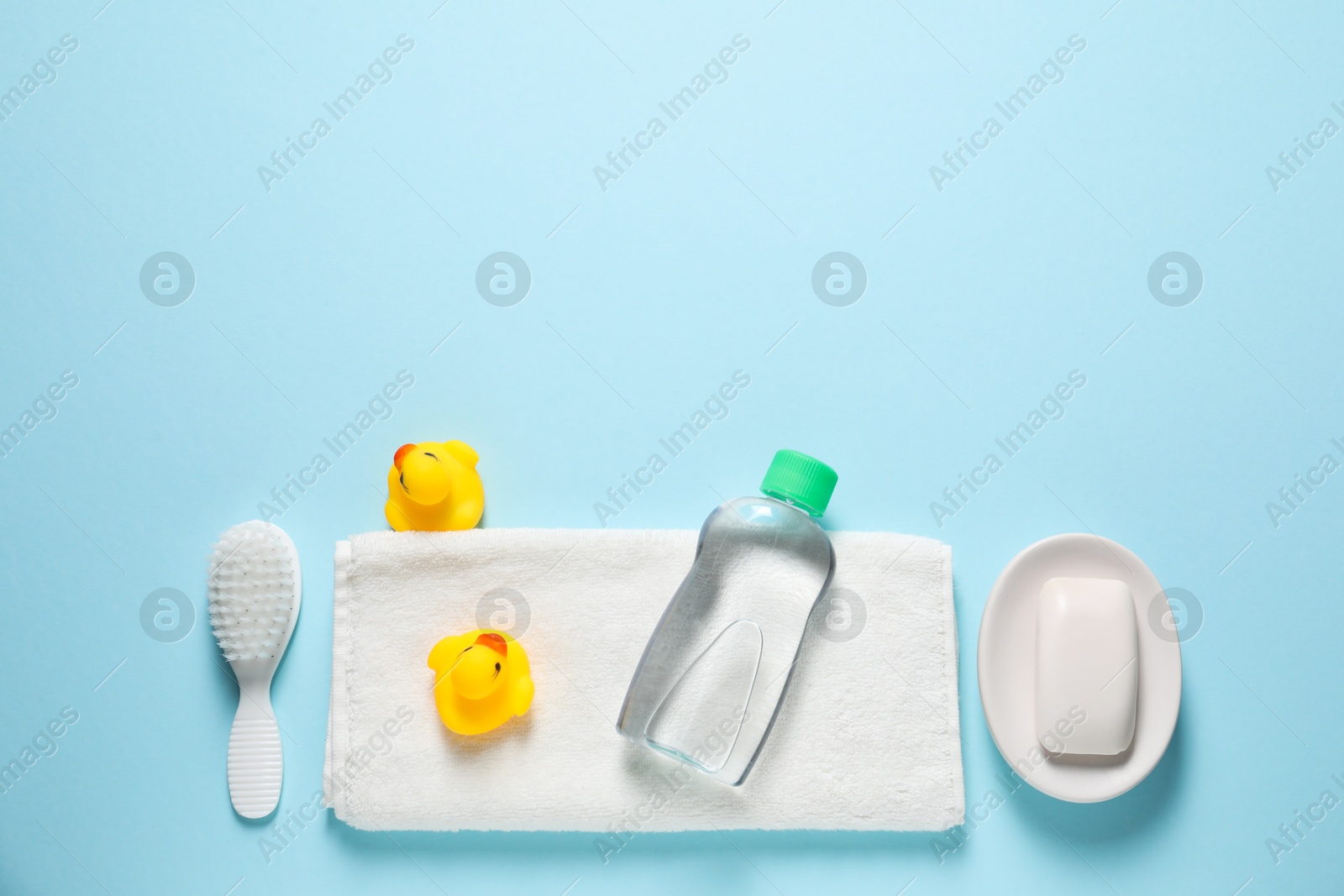 Photo of Baby oil and bath accessories on light blue background, flat lay. Space for text