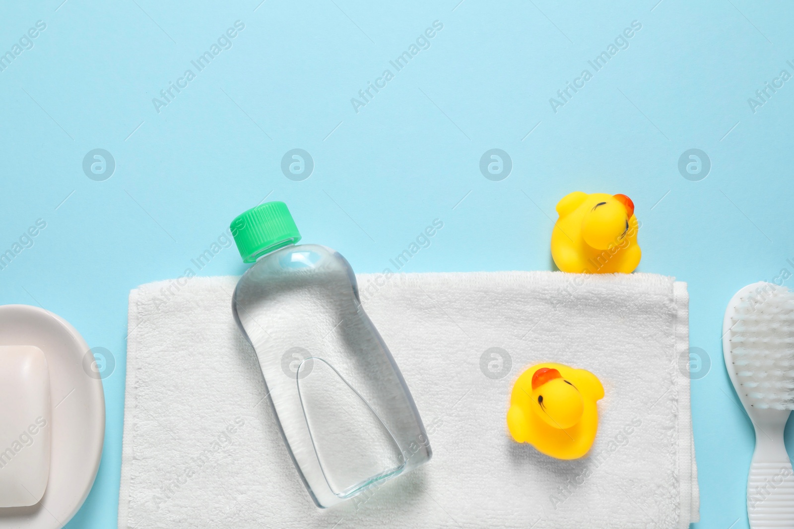 Photo of Baby oil and bath accessories on light blue background, flat lay. Space for text