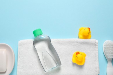 Photo of Baby oil and bath accessories on light blue background, flat lay. Space for text