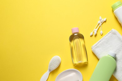 Photo of Baby oil and bath accessories on yellow background, flat lay. Space for text