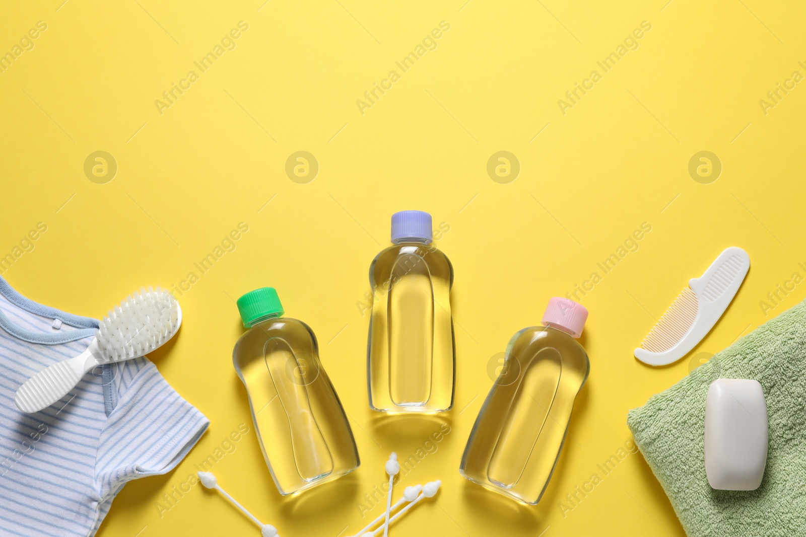 Photo of Baby oil, clothes and bath accessories on yellow background, flat lay. Space for text