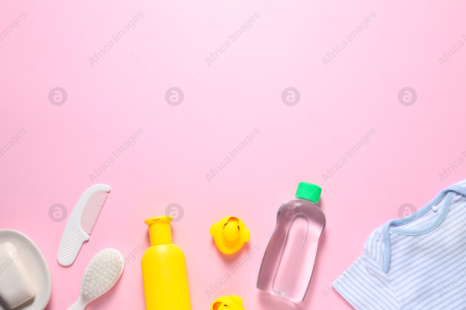 Photo of Baby oil, clothes and bath accessories on light pink background, flat lay. Space for text