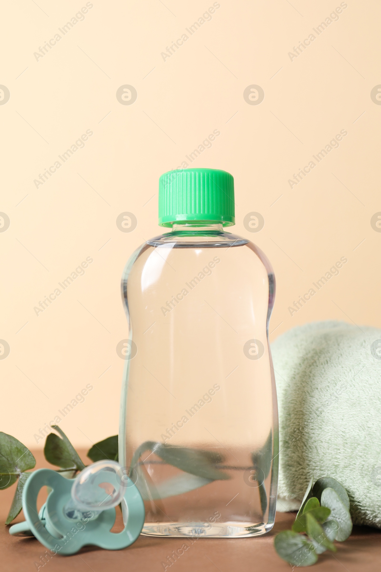 Photo of Baby oil, pacifier, towel and eucalyptus on color background, closeup