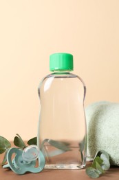 Photo of Baby oil, pacifier, towel and eucalyptus on color background, closeup