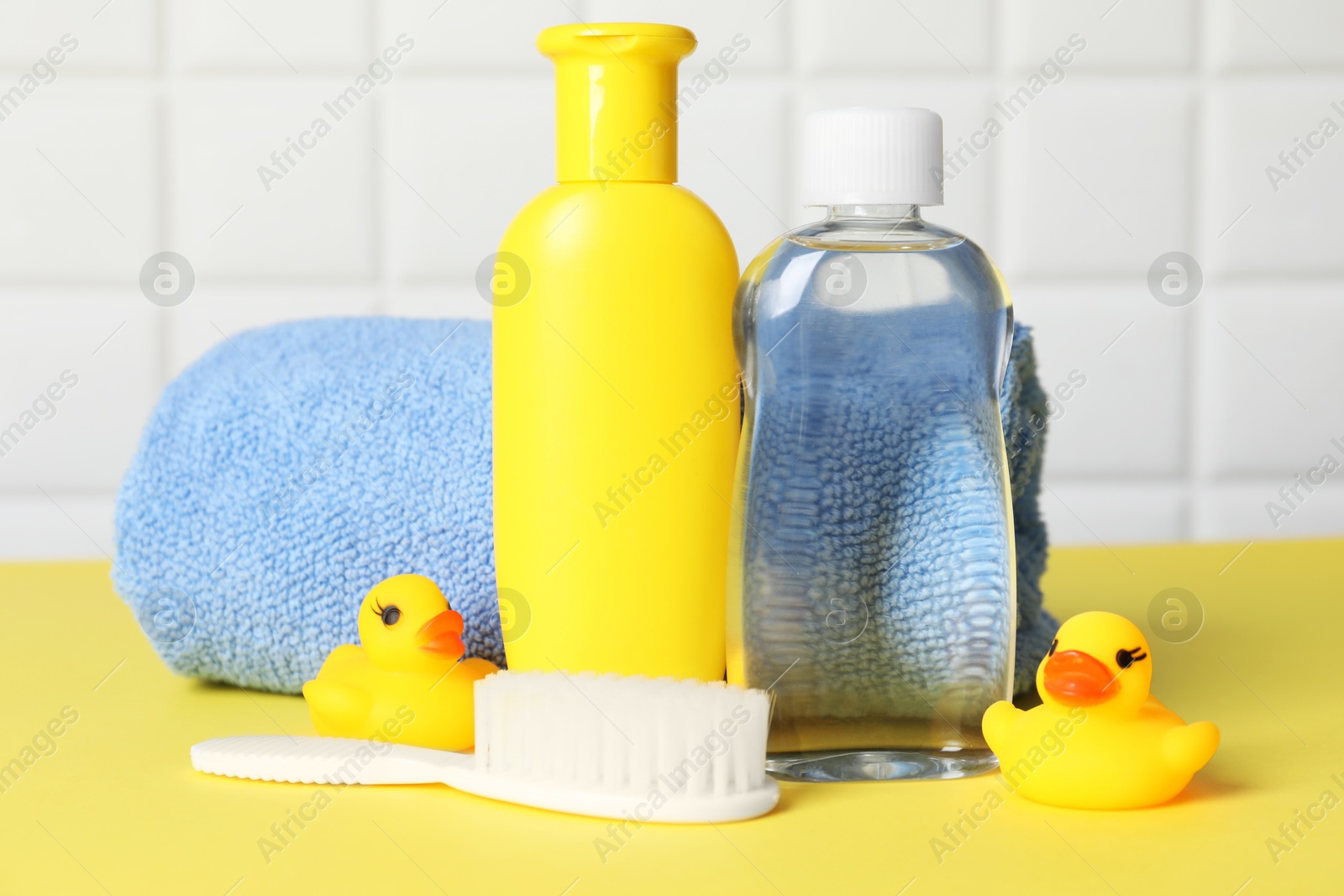 Baby oil and bath accessories on yellow table Photo of Baby oil and bath accessories on yellow table