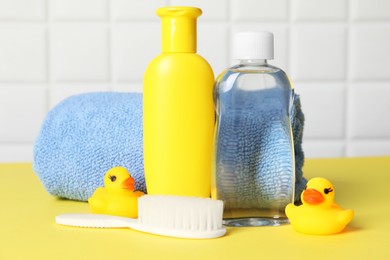 Photo of Baby oil and bath accessories on yellow table