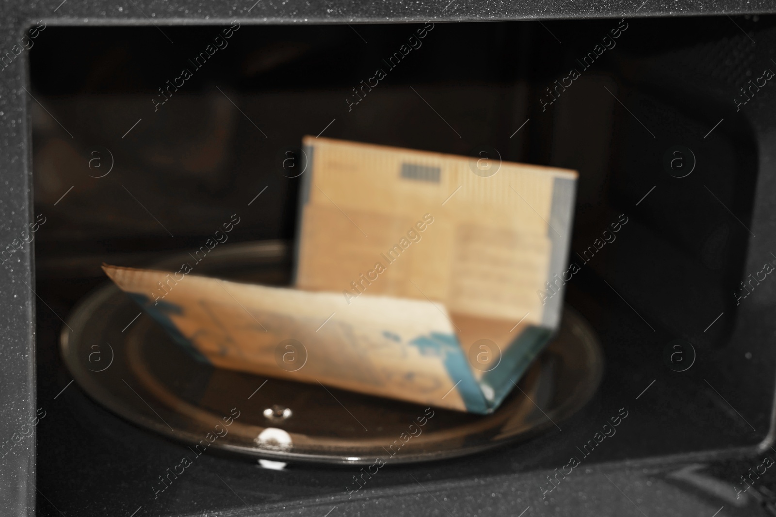 Photo of Bag of popcorn in microwave oven, closeup