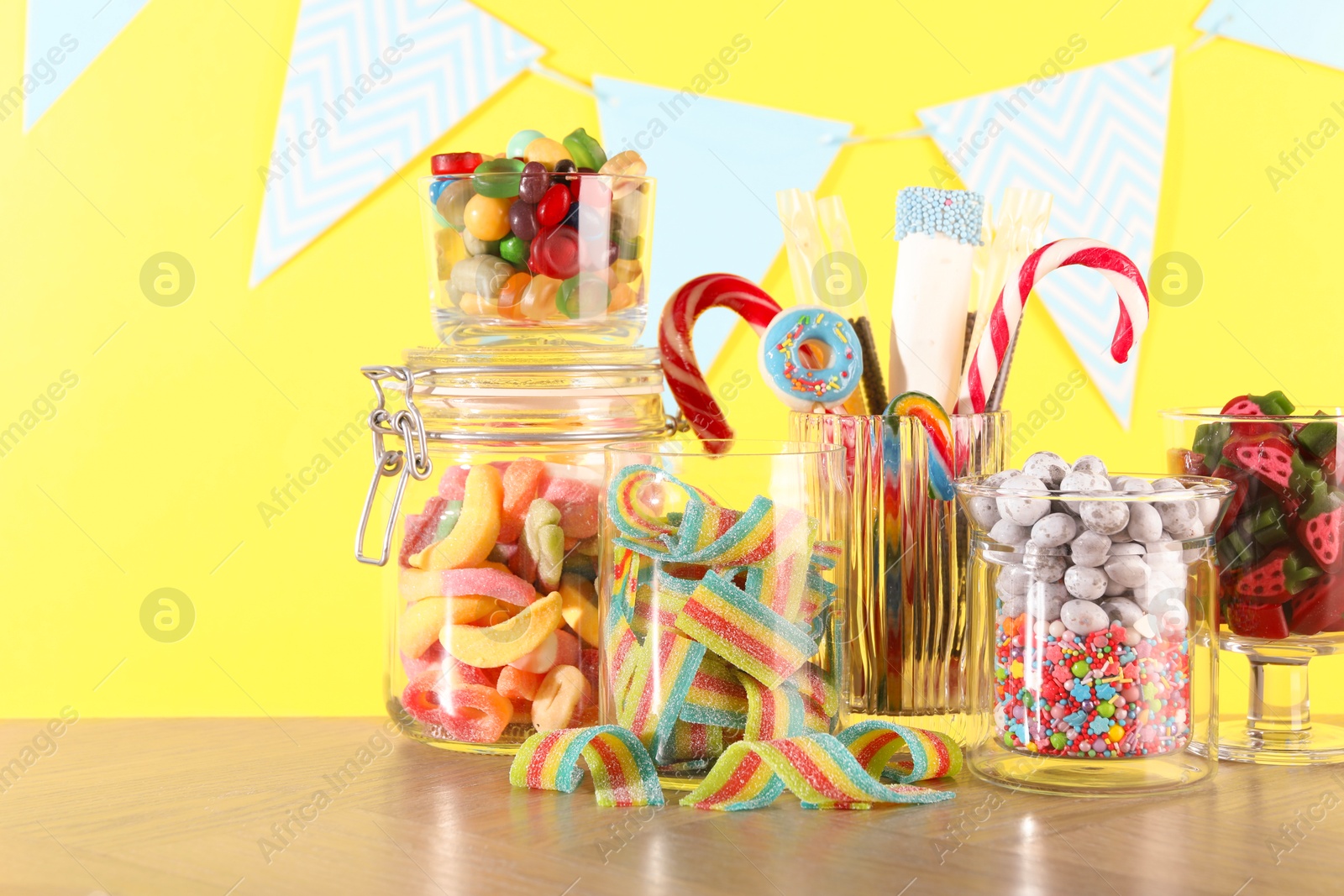 Photo of Candy bar. Many different sweets on wooden table against yellow background